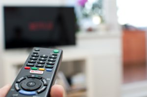 Zagreb, Croatia - March 5, 2016: Photo of a Netflix button on a TV remote with television in the background.